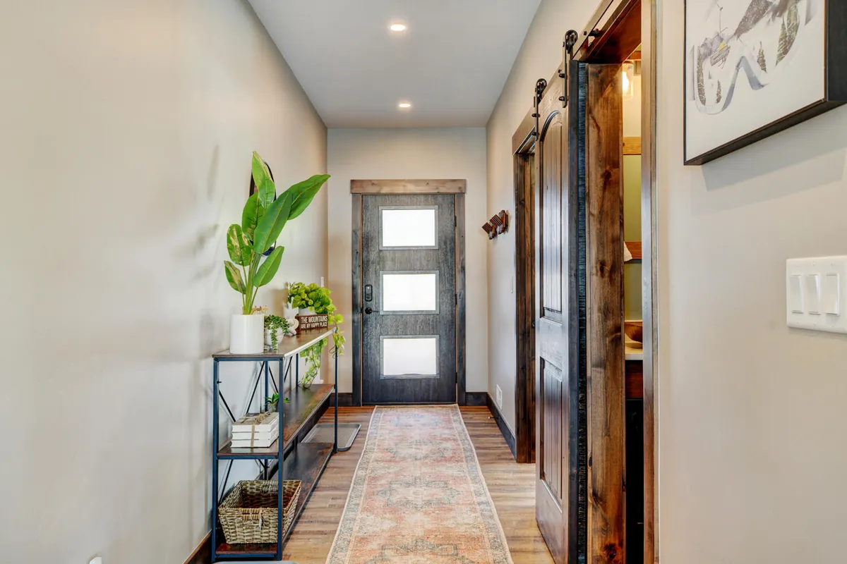 This image captures the inviting entryway of the villa, with the front door, a welcoming console table, a stylish rug, and a touch of greenery from a potted plant. The space feels open, friendly, and ready to receive guests for group gatherings or celebrations.